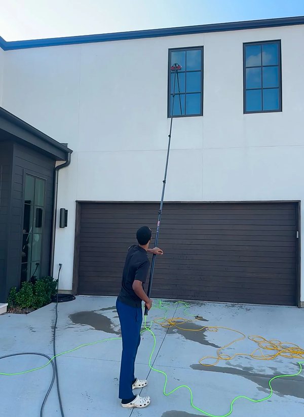 A technician cleaning upper storey windows with a water fed pole